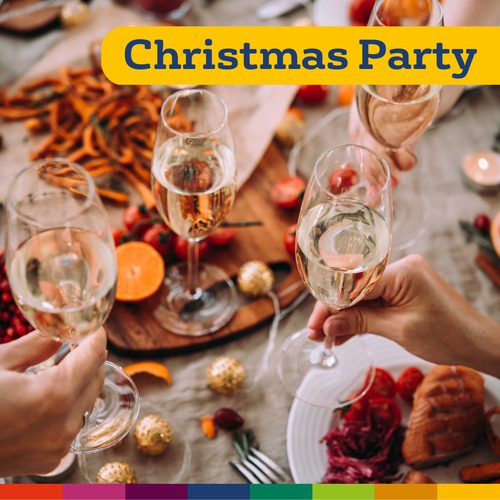 Quatro pessoas brindam com taças de champanhe sobre uma mesa festiva com comida, decorações e uma faixa com os dizeres "Festa de Natal" no topo, capturando o espírito alegre de uma celebração de Natal em Manchester.