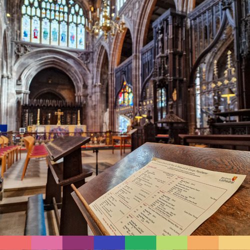 L'interno di una chiesa con vetrate colorate, panche di legno e un leggio in primo piano evoca la serena atmosfera della cattedrale di Manchester.