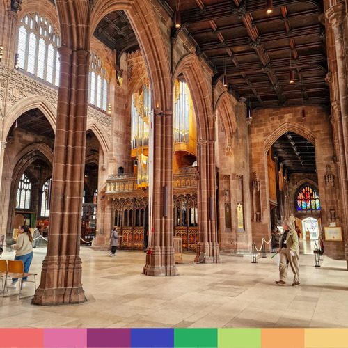 Interno della grande e storica Cattedrale di Manchester, con alte colonne, vetrate e un importante organo a canne. Alcune persone passeggiano o sono sedute all'interno.