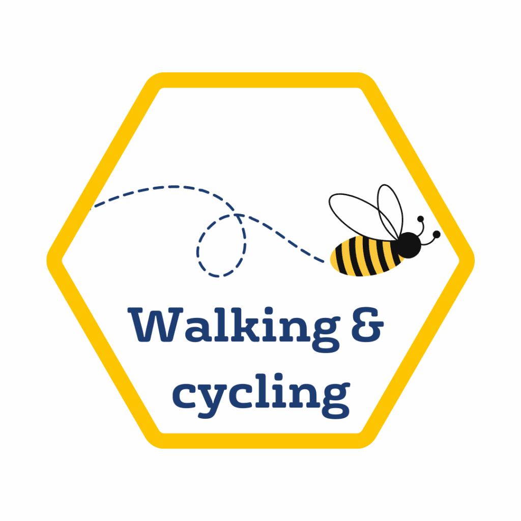 Hexagonal sign with a yellow border, an illustrated bee, a dashed flight path, and the text "Walking & cycling" in blue letters—part of the Public Transport in Manchester network.