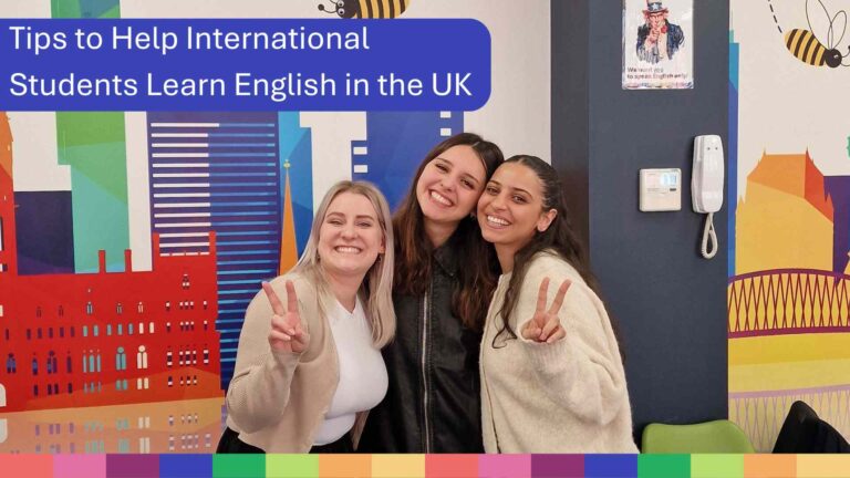 Drei junge Frauen lächeln und posieren mit Friedenszeichen in einem farbenfrohen Raum. Auf einem Banner steht „Tipps für internationale Studierende, die in Großbritannien Englisch lernen“ und zeigt spielerisch Möglichkeiten, ihre Sprachkenntnisse im Ausland zu verbessern.